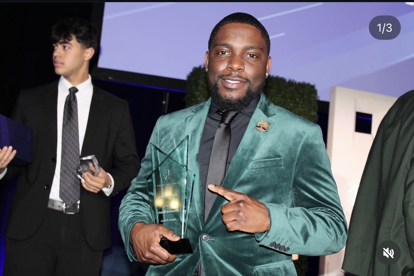 Fine Line Vision team member receiving an award in a green velvet suit